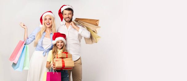 Familie in Weihnachtsmützen mit Weihnachtsgeschenken auf weißem Hintergrund - Foto, Bild