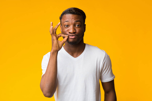 Afro Man maken Zip Lip Gesture Staande, Studio Shot - Foto, afbeelding