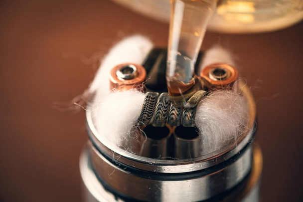atomizador de goteo reconstruible o RDA para vapear o e-cigarrillo con bobina y rayas de algodón mojadas con e-líquido
 - Foto, Imagen