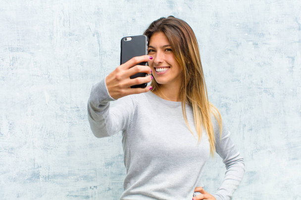 young pretty woman with a smart phone against grunge wall - Foto, Imagem