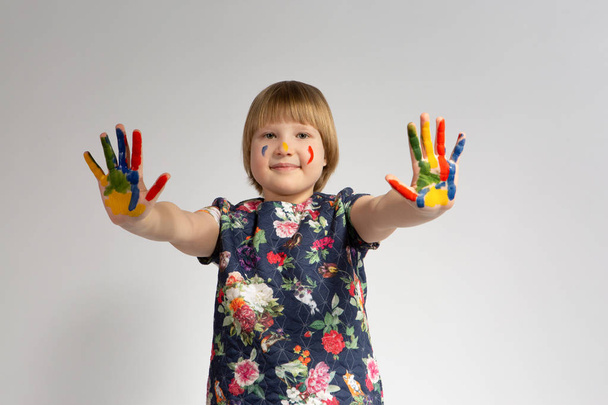 Linda niña con manos pintadas de colores sobre fondo blanco aislado
 - Foto, Imagen