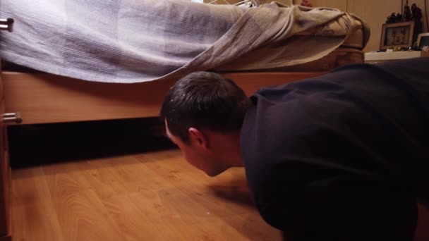 Młody człowiek myje podłogę w domu. Zbliżenie mężczyzny wycierającego brud z drewnianej podłogi specjalną szmatką. - Materiał filmowy, wideo