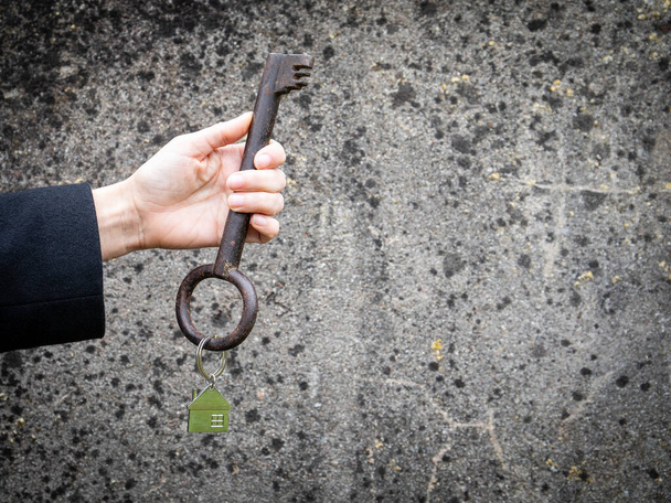Holding big, old style key with house type brelox - Φωτογραφία, εικόνα