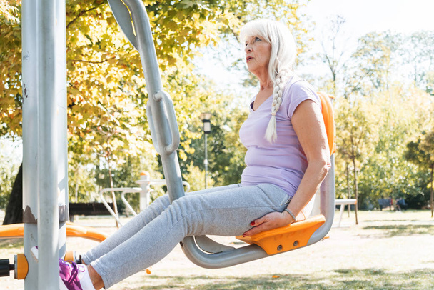 Energetic senior gray haired woman training in city park  - Foto, imagen