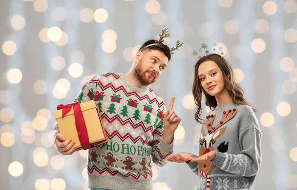 happy couple in ugly sweaters with christmas gift - Fotografie, Obrázek