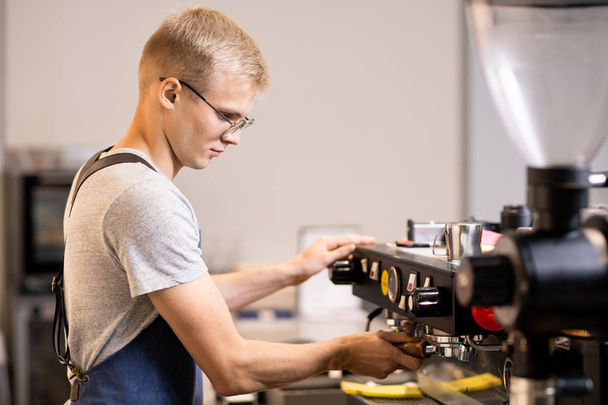 Komoly fiatal barista, a tulajdonos a kis hangulatos kávézó, fog készíteni kávét ügyfeleinek, miközben áll a munkahelyen - Fotó, kép