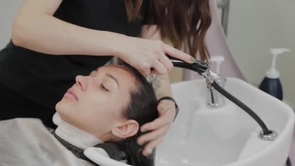 mooi jong meisje wassen hun haar op de kapper. - Video