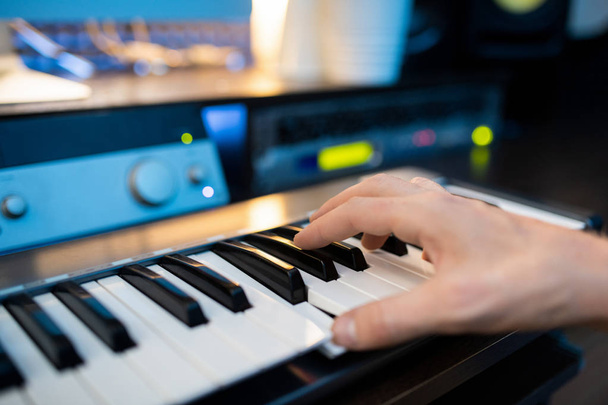 Рука піаніста, який натискає одну з клавіш клавіатури піаніно під час запису музики в сучасній студії
 - Фото, зображення