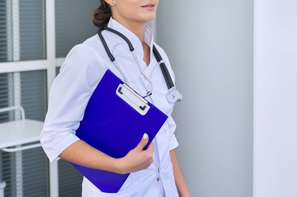 Portrait of young female medical doctor with stethoscope clipboard at hospital - Foto, afbeelding
