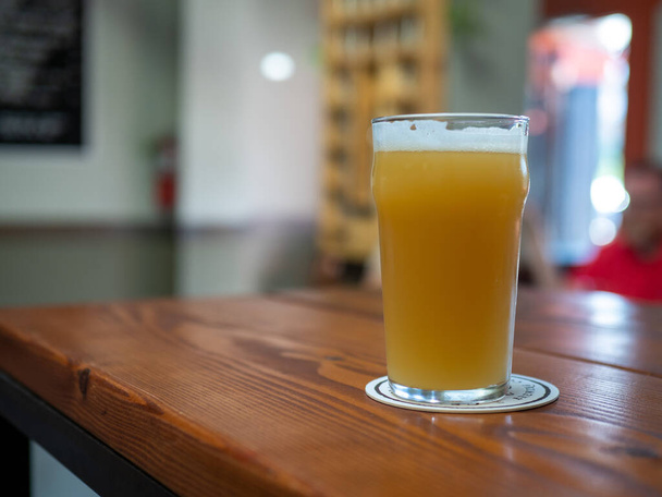 Plně čerstvě nalitá sklenice piva s pěnou na hlavě na stole restaurace - Fotografie, Obrázek