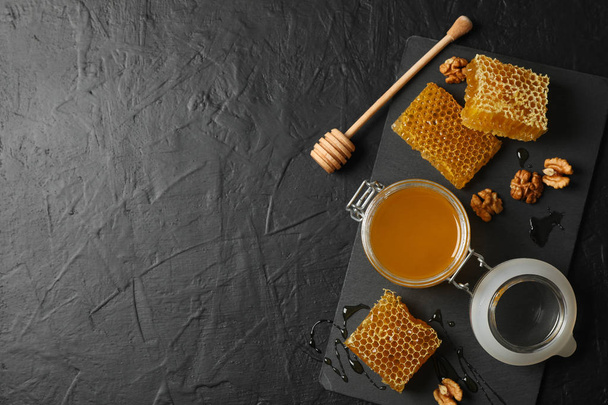 Walnut, honeycombs, jar with honey and dipper on black backgroun - Photo, Image