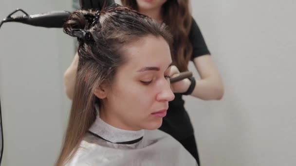 Девушка парикмахер сушит волосы для клиента с феном в парикмахерской
. - Кадры, видео