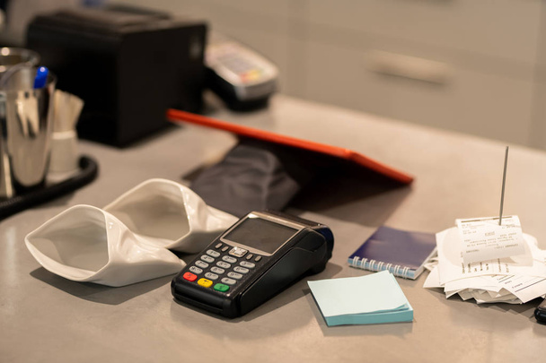Elektronische betaalautomaat, twee kleine lege zakken voor wisselgeld, briefpapier en stapel ontvangstbewijzen op de werkplek van accountant - Foto, afbeelding