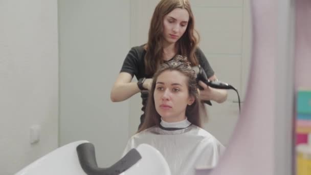 Meisje kapper droogt haar naar klant met haardroger bij kapper. - Video