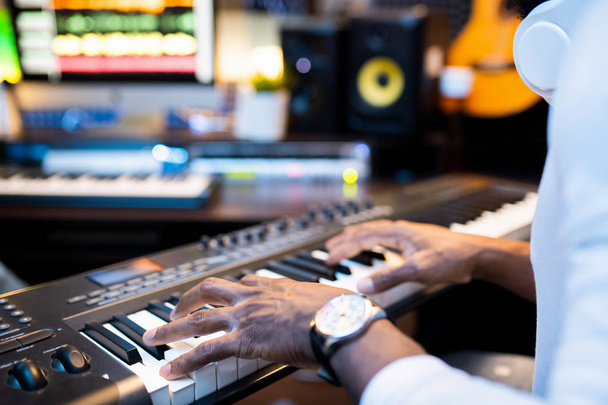Mãos de jovem músico afro-americano sobre chaves de pianoboard trabalhando sozinho no estúdio de gravação de som contemporâneo
 - Foto, Imagem