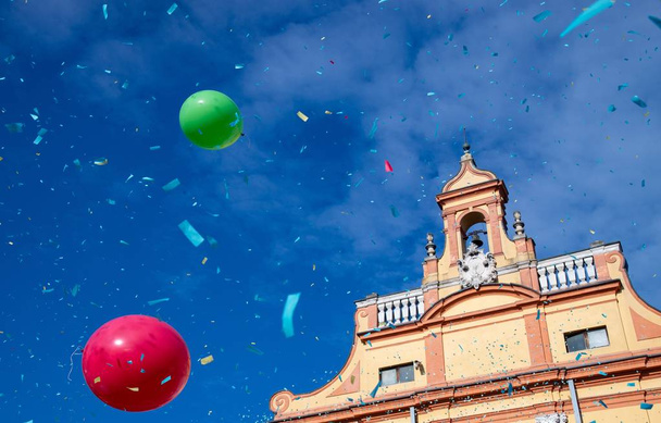 Piazza del Guercino in Cento, Ferrara, Italy, during the famous carnival. Against the blue sky, throwing confetti, balloons, life jackets. - 写真・画像