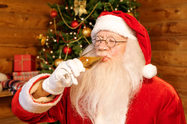 Mikulás pezsgőt iszik, miközben ünnepli a karácsony december végén, miközben otthon marad - Fotó, kép