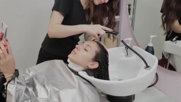 schöne junge Mädchen waschen ihre Haare beim Friseur. - Filmmaterial, Video