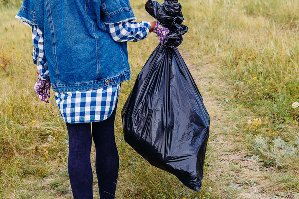 a large black garbage bag in the hands of a female volunteer - Foto, imagen