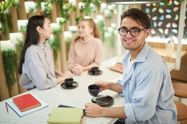 Multi-etnische groep studenten die samen studeren in café, focus op mixed-race jonge man glimlachen op camera, kopieer ruimte - Foto, afbeelding