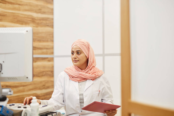 Retrato de una mujer árabe joven usando máquinas electrónicas mientras trabajaba como médico en una clínica médica, espacio para copiar
 - Foto, imagen