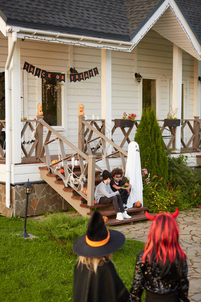Широкий угол зрения на группу детей, идущих в украшенный дом во время трюка или лечения на Хэллоуин, копировать пространство
 - Фото, изображение