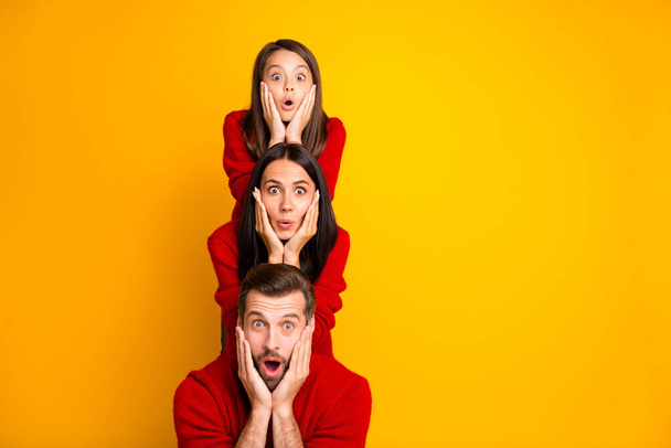 Photo of excited crazy trendy cheerful cute funky positive family having built pyramid with their bodies astonished facial expression wearing red sweaters isolated over vivid color yellow background - Foto, immagini