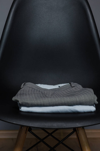 μαύρη καρέκλα με μια στοίβα από ρούχα - Φωτογραφία, εικόνα