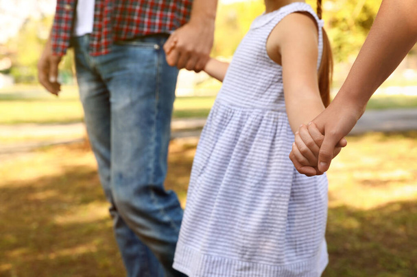 Little girl and her parents holding hands outdoors, closeup. Family weekend - Photo, Image