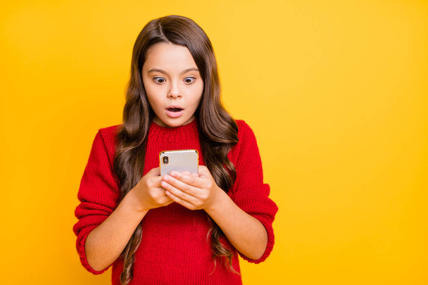 Portrait of astonished negative child use her smartphone stare stupor get notification dislike in her blog wear stylish trendy pullover isolated over yellow color background - Zdjęcie, obraz