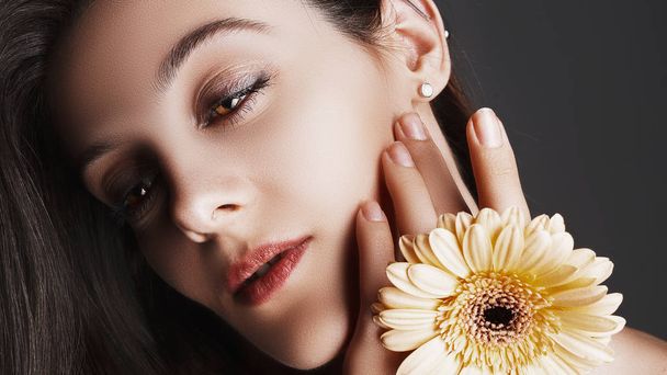 Beauty face of the young beautiful girl with flower. Perfect Skin. Professional Make up. Fashion Art - Photo, Image