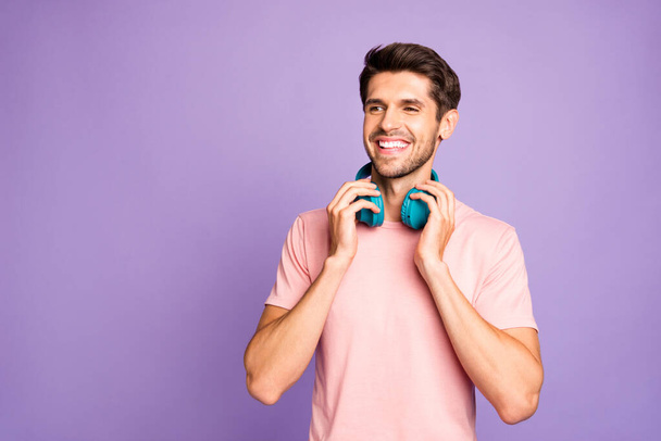 Portrait of his he nice attractive cheerful cheery guy wearing pink tshirt bluetooth earphones enjoying stereo sound isolated on violet purple lilac pastel color background - Foto, Bild