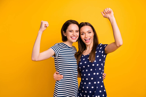 Photo of two amazing ladies celebrating beginning low shopping prices season raising fists wear summer casual trendy dresses isolated yellow background - Fotoğraf, Görsel