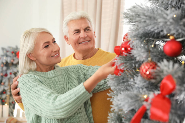 Happy mature couple decorating Christmas tree at home - Photo, Image