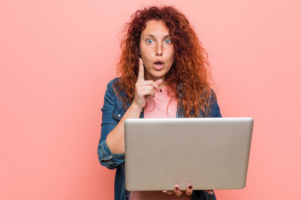 Young caucasian redhead woman holding a laptop having some great idea, concept of creativity. - Φωτογραφία, εικόνα