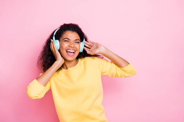 Cool song. I like it. Portrait of funky cheerful crazy african girl have headset listen playlist enjoy melody sing feel fun on break pause wear yellow pullover sweater isolated pastel color background - Фото, изображение
