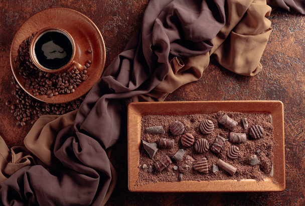 Čokoládové bonbóny v čokoládových lupíncích a káva na staré hnědé  - Fotografie, Obrázek