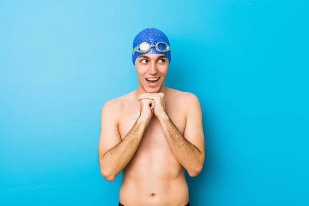 Young swimmer man keeps hands under chin, is looking happily aside. - Foto, Bild