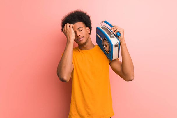 Молодой африканский американец держит винтажное радио взволнованным и подавленным
 - Фото, изображение