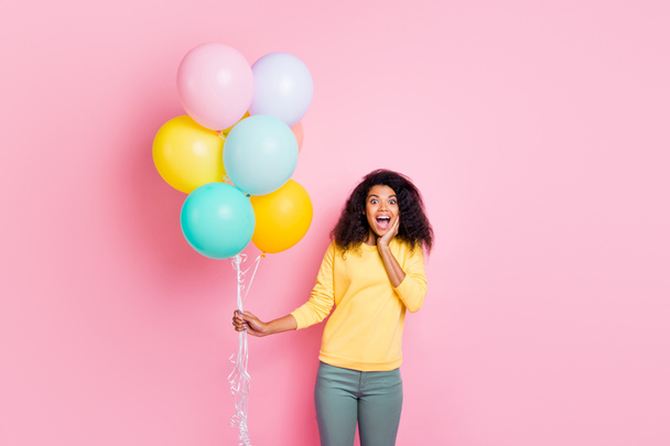Portrait of excited shocked girl hold many balons get gift for anniversary 8-march impressed scream wow omg wear yellow pullover pants isolated over pastel color background - Фото, изображение