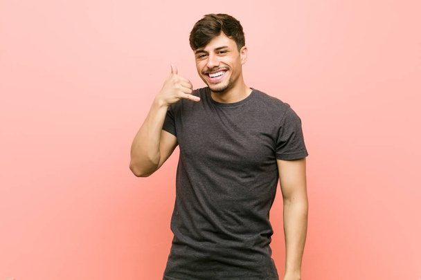 Young hispanic casual man showing a mobile phone call gesture with fingers. - Photo, Image