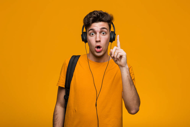 Jonge coole student man luisteren naar muziek met koptelefoon ontspannen denken over iets op zoek naar een kopieerruimte. - Foto, afbeelding