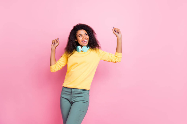 Portret van vrolijke leuke positieve Afrikaanse meisje dans veel plezier genieten feest evenement vakantie dragen gele trui broek geïsoleerd over roze kleur achtergrond - Foto, afbeelding