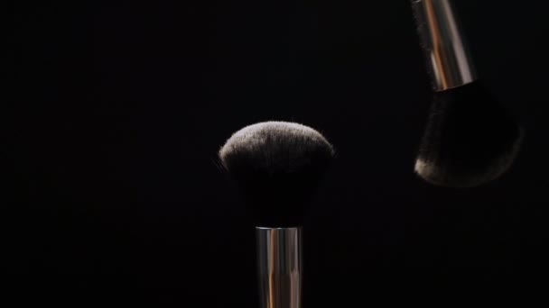 Two black makeup brushes with powder or blush on a dark background. Beauty concept - Záběry, video