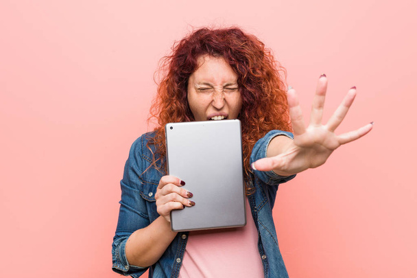 Young caucasian redhead woman holding a tablet shouting excited to front. - Foto, immagini