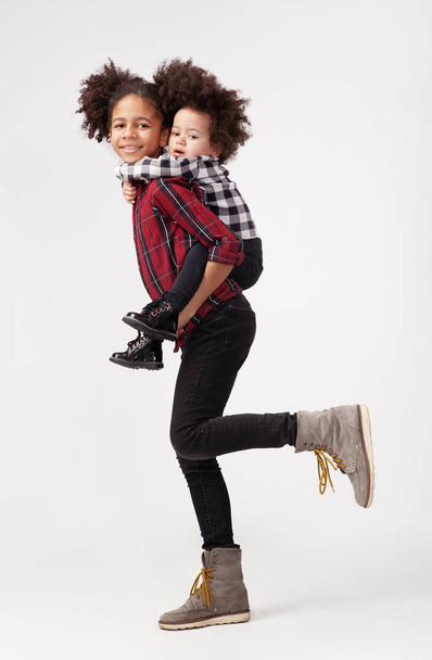 Teenage girl giving her little sister a piggyback ride  - Zdjęcie, obraz