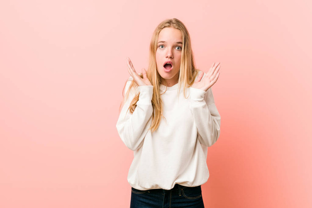 Young blonde teenager woman surprised and shocked. - 写真・画像