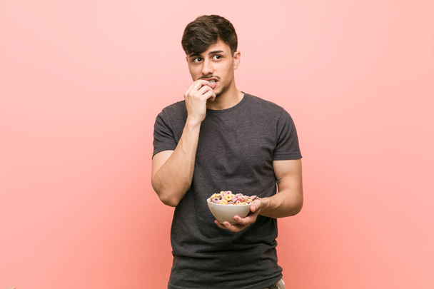 Young hispanic man holding a cereal bowl relaxed thinking about something looking at a copy space. - Foto, afbeelding