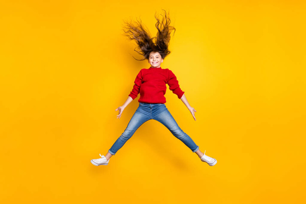 Full size photo of excited pretty little lady jumping high hairdo flying air amazing weekend mood wear red knitted pullover and jeans isolated yellow background - Фото, зображення