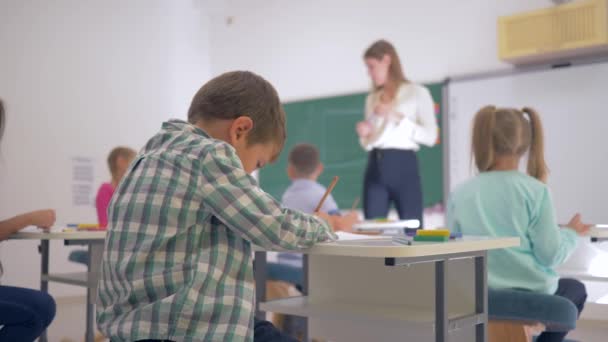 portrét šťastného školáčka na stole při výuce ve třídě na Juniorské škole zblízka - Záběry, video